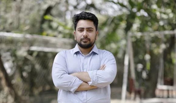 Person standing outdoors with arms crossed.